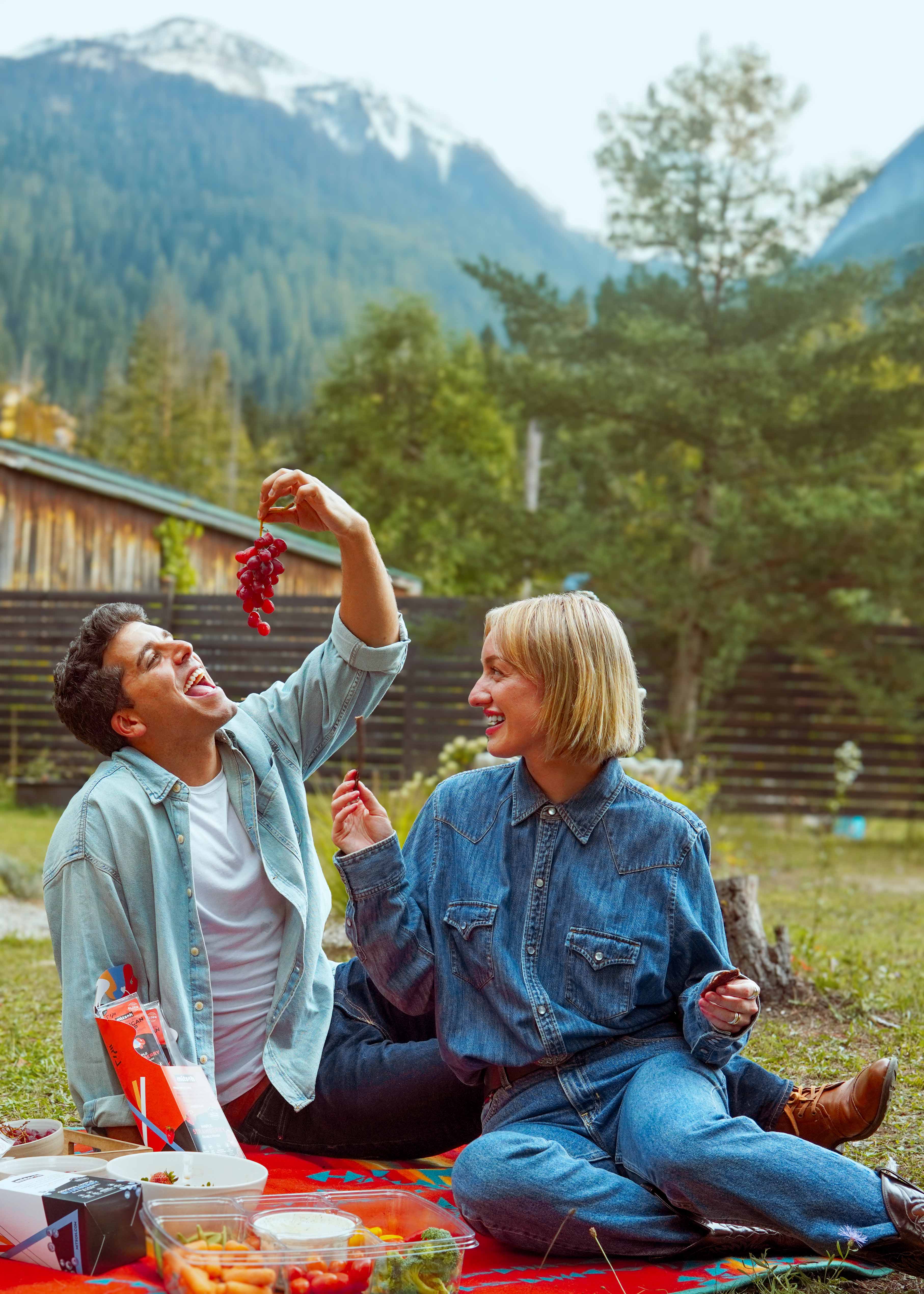 Friends enjoying Mitsoh bison pemmican snacks and fresh fruit at a mountain picnic