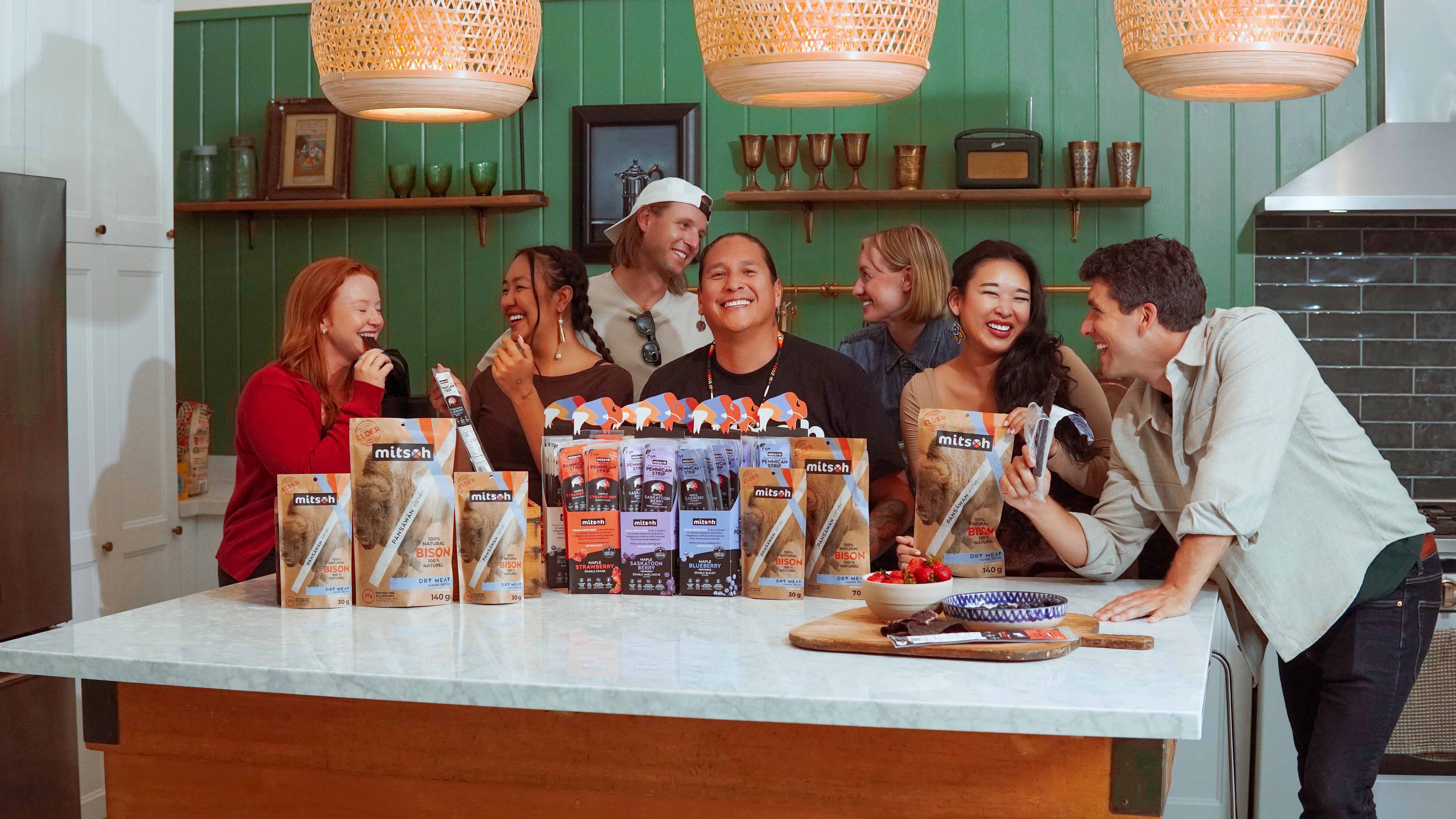 Mitsoh founder Ian Gladue and team gathered around a kitchen island with Mitsoh bison snacks
