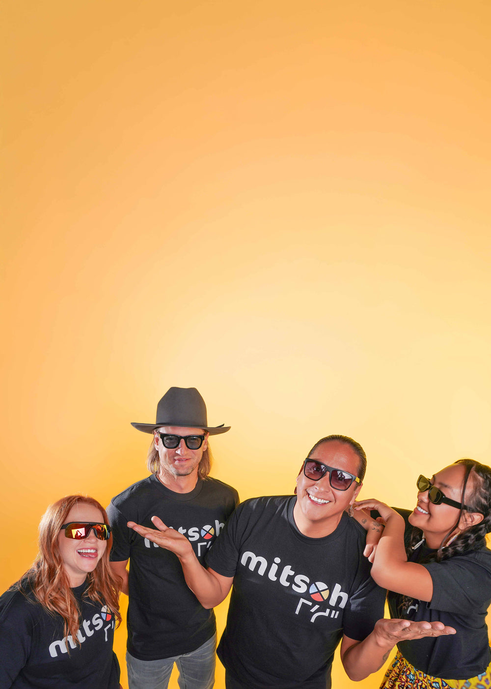 Mitsoh founder Ian Gladue and team members wearing Mitsoh shirts against a yellow studio background